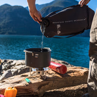 MSR Dromedary Bag in use pouring water into a camp stove pot